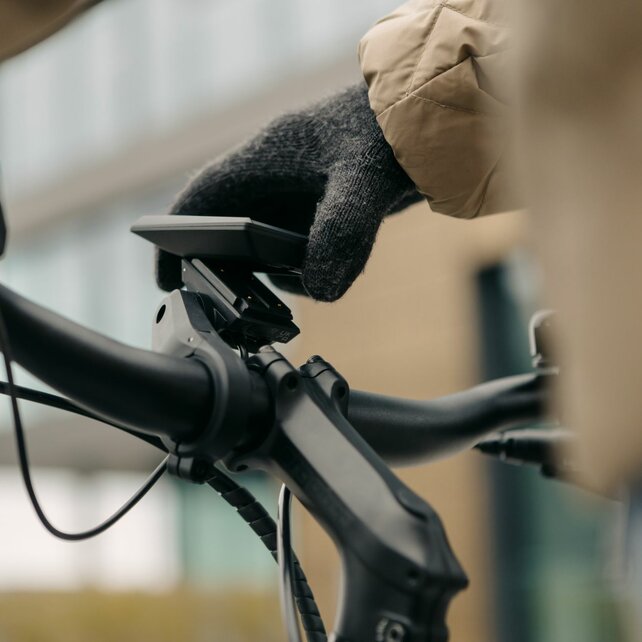 A gloved hand inserts a Kiox 300 display into the mount.