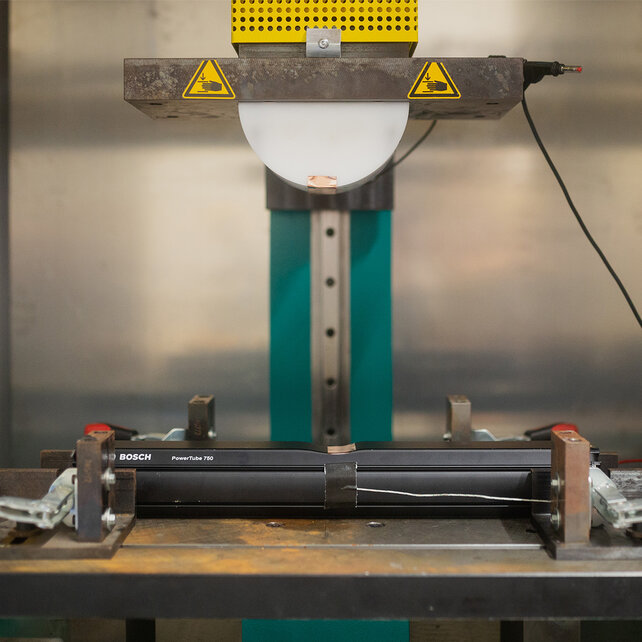 Die PowerTube 700 ist auf einer Werkbank einer Maschine eingespannt, die zur Prüfung der Stabilität dient. Im Hintergrund sind silberne Wände zu sehen.
