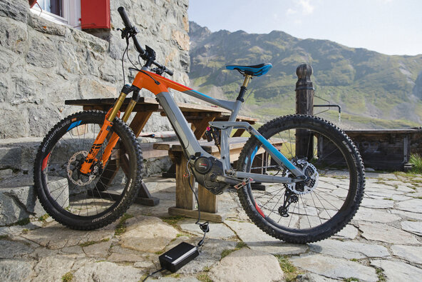 eMountainbike vor Berghütte, das gerade mit einem Bosch eBike Charger aufgeladen wird