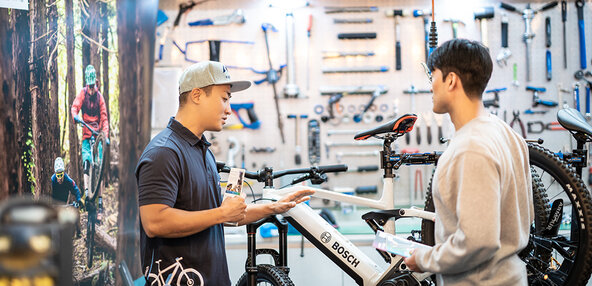 Mechanic & Customer talking in front of Bike and holding brochure