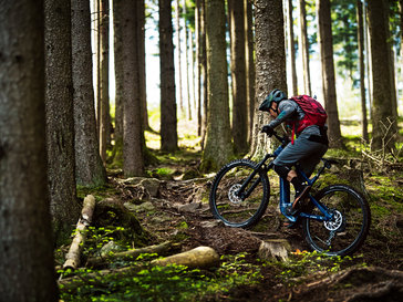Ein eBiker fährt mit seinem eMountainbike einen steilen Trail im Wald hinauf