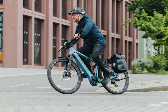 Ein Mann fährt mit seinem eBike in einer Rechtskurve.