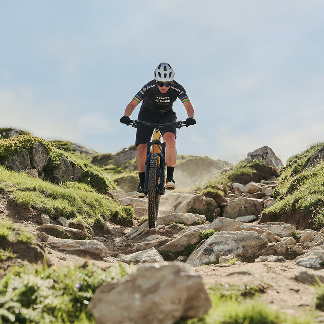 Un VTT à assistance électrique descend une pente sur des pierres.