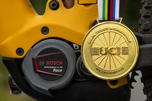 Close-up of a Performance Line CX Race Drive Unit at a yellow eBike with a gold medal hanging in front of it.