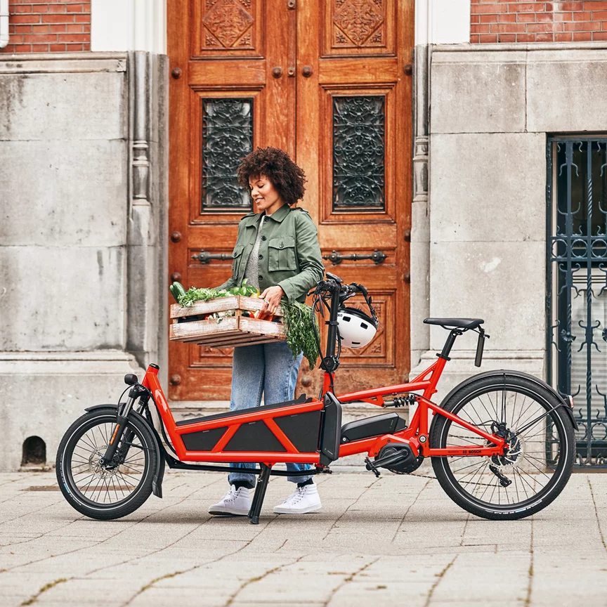 A woman loads her eCargo bike with a crate of vegetables
