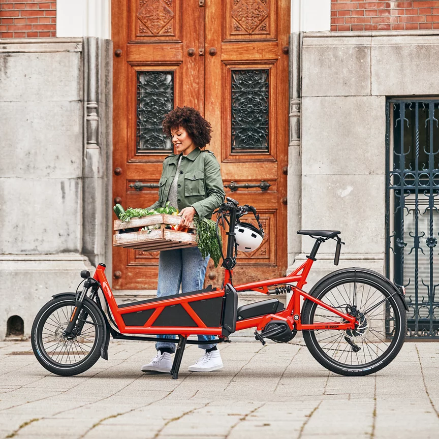 A woman loads her eCargo bike with a crate of vegetables