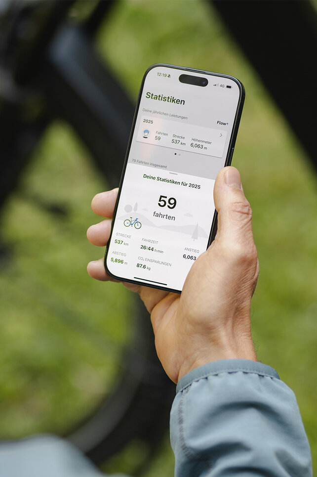 Eine Person hält ein Smartphone in der Hand und schaut sich die Statistiken in der eBike Flow App an.