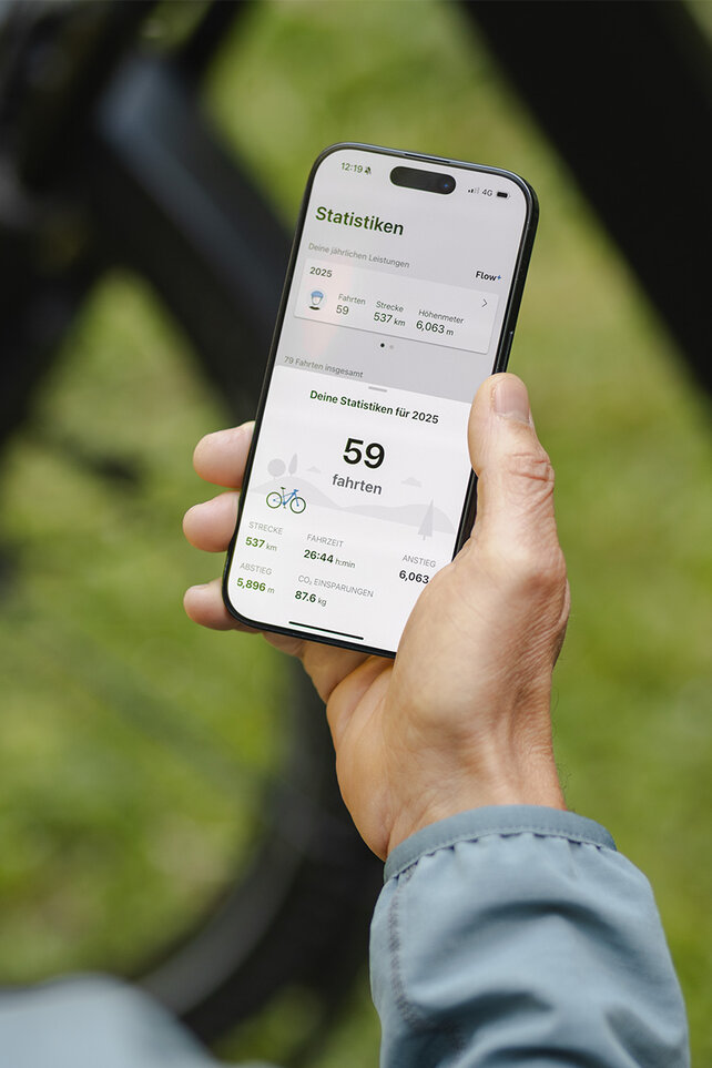Eine Person hält ein Smartphone in der Hand und schaut sich die Statistiken in der eBike Flow App an.