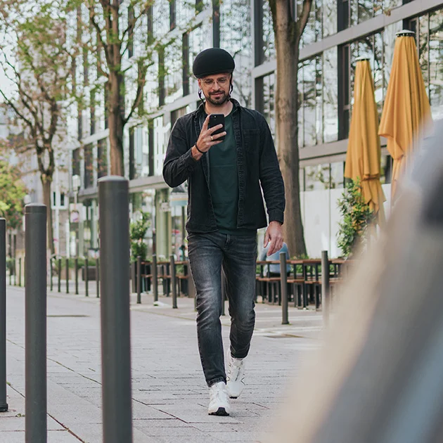 A man walks towards his eBike in the city and checks his smartphone.