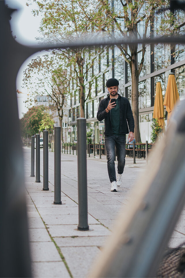 A man walks towards his eBike in the city and checks his smartphone.