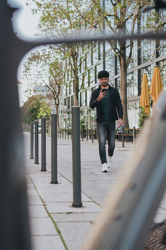 Mannen går mot sin elcykel i staden och tittar på sin smartphone.