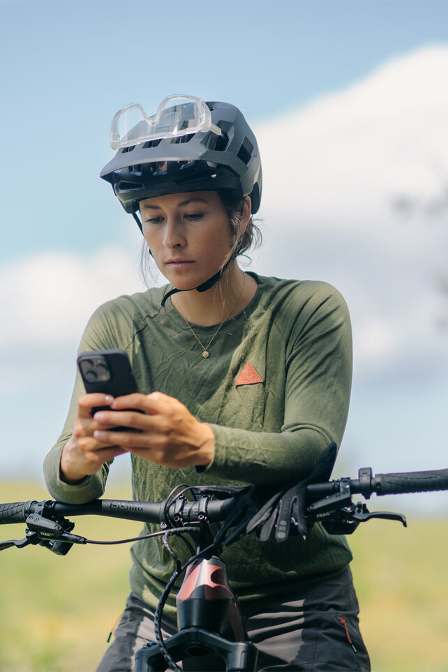 The eBiker looks at her smartphone with nature in the background.