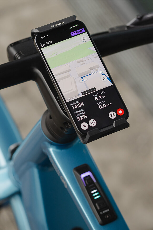 Zbliżenie pionowego SmartGrip przymocowanego do kierownicy. Smartfon działa w trybie nawigacji i wyświetla prowadzenie po trasie.