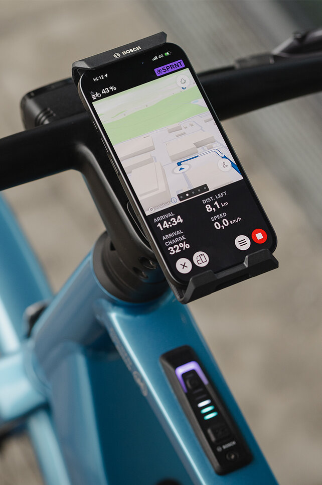 Nærbilde av en SmartphoneGrip Vertical festet til et styre. Smarttelefonen er i navigasjonsmodus og viser en ruteveiledning.