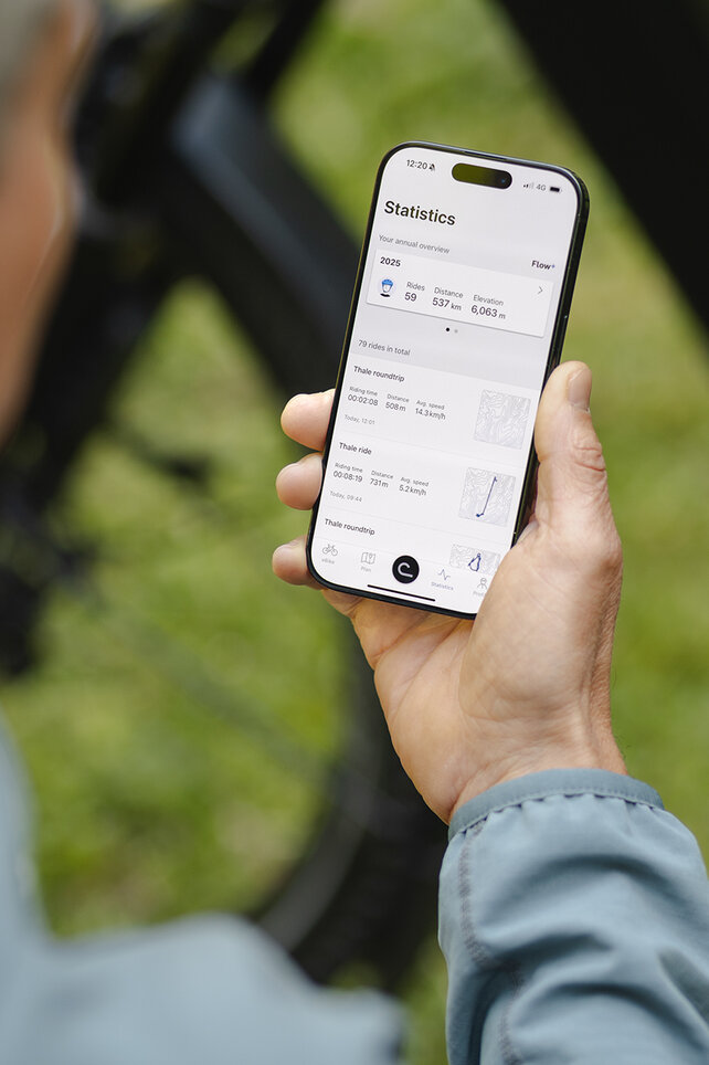 Guardando oltre la spalla di un uomo che consulta le sue statistiche nell'app eBike Flow.