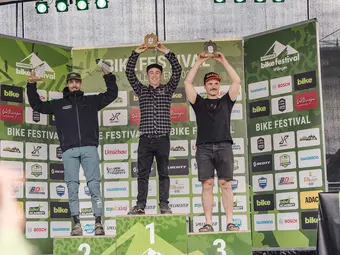 Winners’ podium at the bike festival, with three men joyfully holding up trophies.