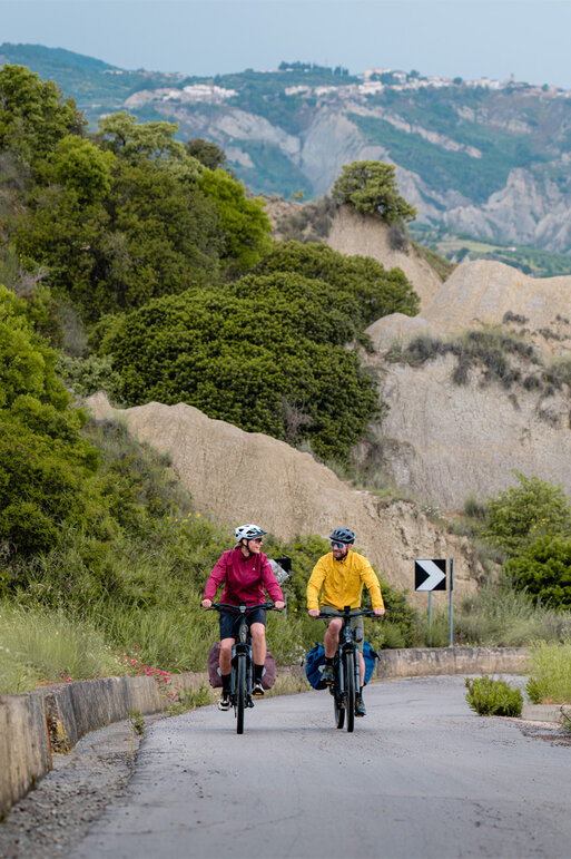 Eine Frau und ein Mann fahren mit ihren eBikes einen Berg hinauf.