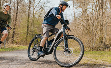 The eBike rider drives around the bend on a path in the forest.