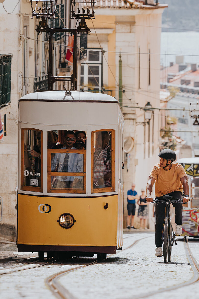 A [M] rides his [eBike] up a hill in the [city] next to an old tram while looking to the side.