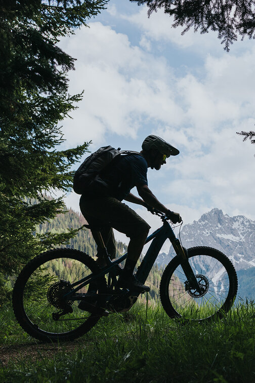An eBiker riding on a mountain meadow and a mountain path in South Tyrol.