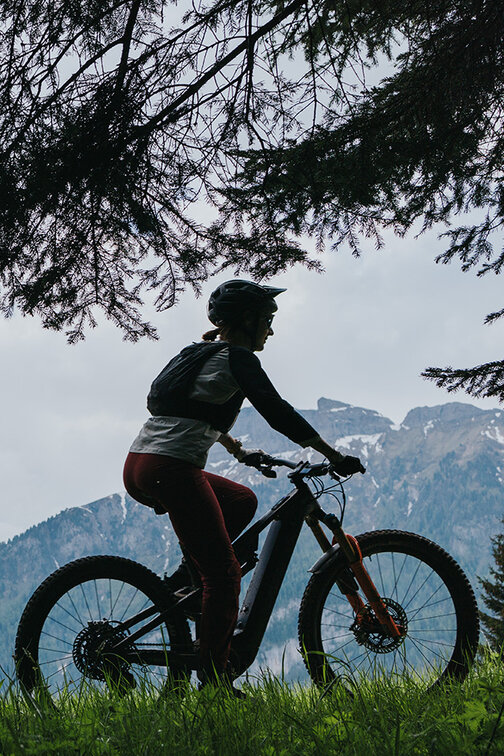 Eine eBike Fahrerin die auf einer Bergwiese und einem Bergpfad in Südtirol fährt.