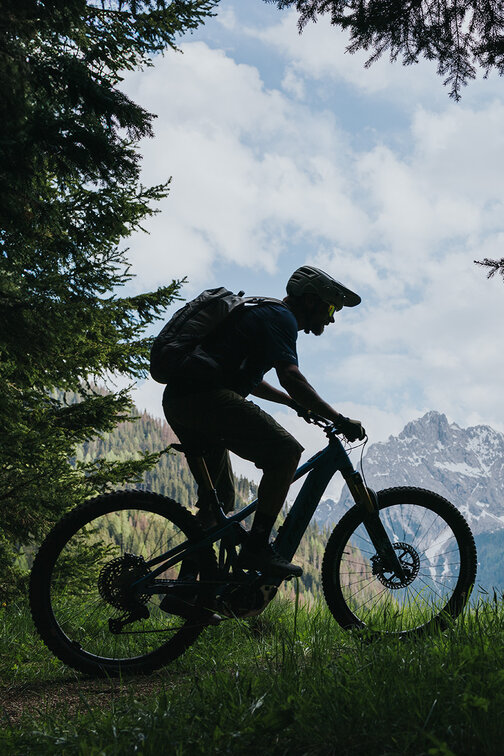 Ein eBike-Fahrer der auf einer Bergwiese und einem Bergpfad in Südtirol fährt.