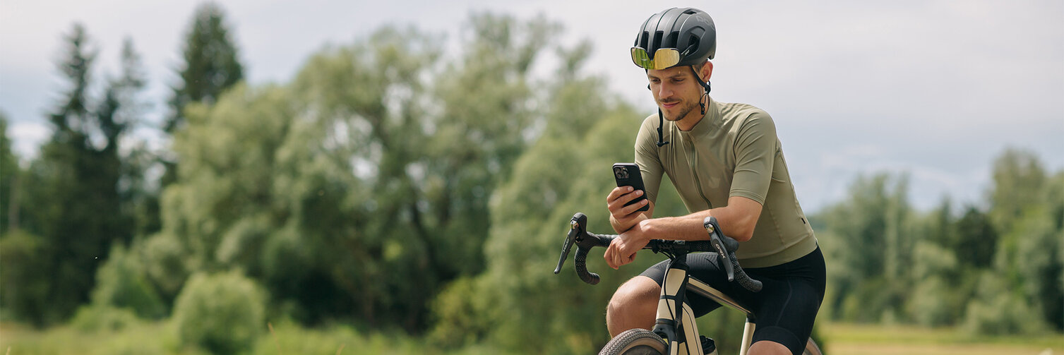 Mężczyzna zrobił przerwę na swoim eRowe, spoglądając na swój smartfon. W tle rozpościerały się łąki i lasy.