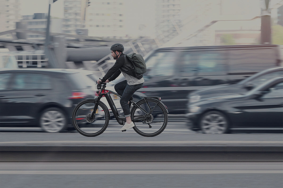 The eBike rider is cycling on a busy road, with the cars in the background blurred.