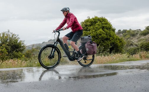 eBikern kör sin elcykel över en vattenpöl.