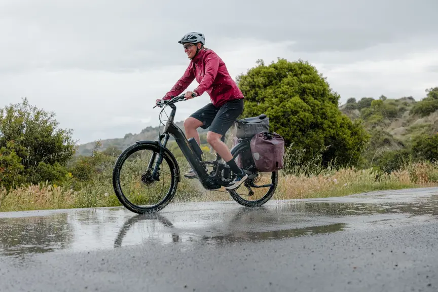 An eBiker rides her eBike through a puddle.
