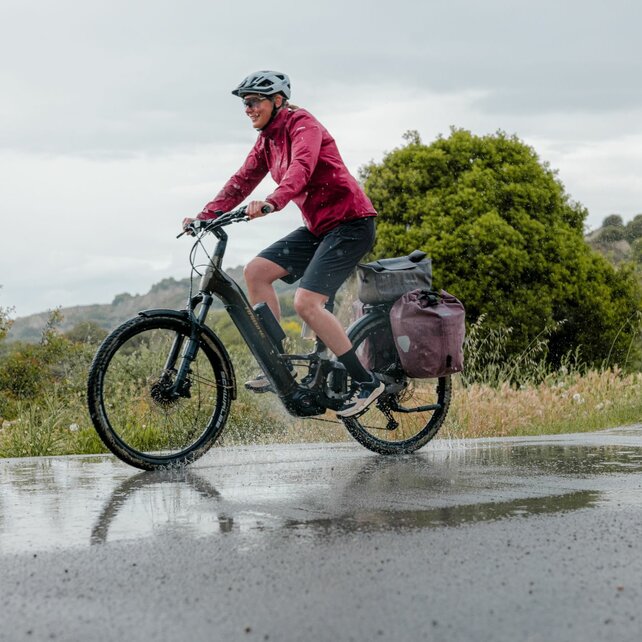 An eBiker rides her eBike through a puddle.