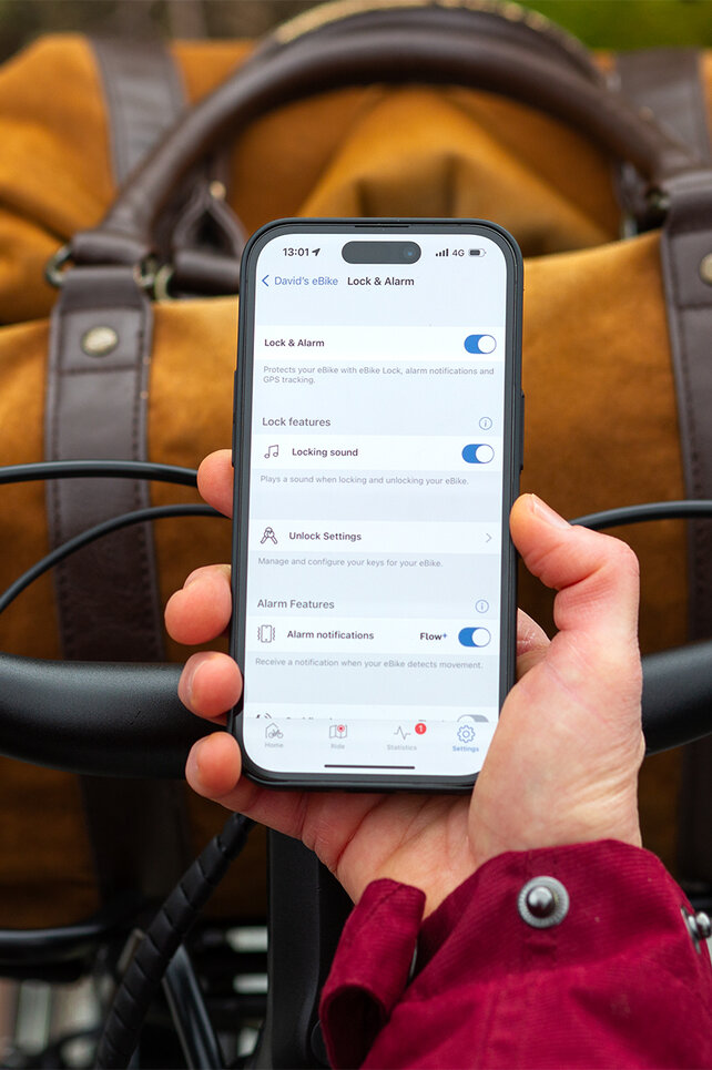 Over de schouder meekijken van iemand die een smartphone vasthoudt en instellingen aanpast voor eBike Lock en alarm in de eBike Flow-app.