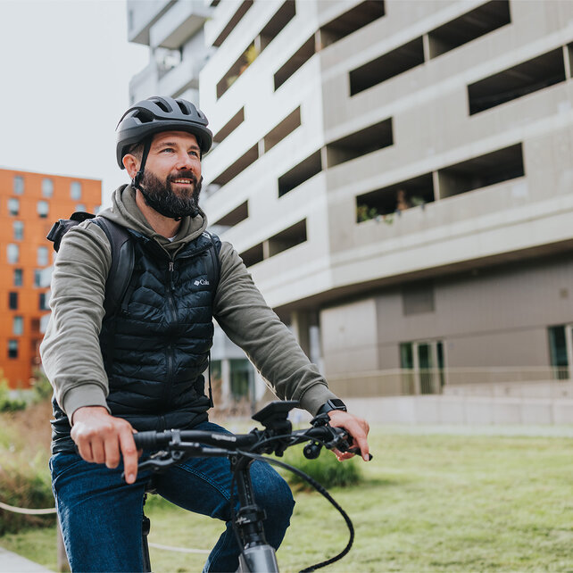 eBiker rides his eBike along houses with a smile.