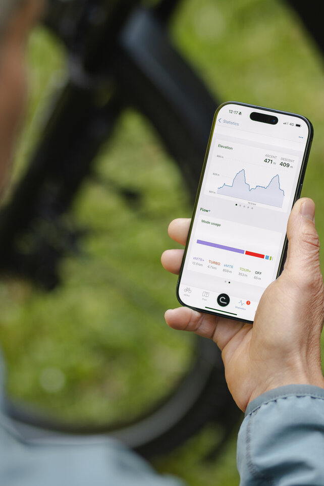 Ser over skulderen til en mann som ser på statistikken sin i eBike Flow-app.