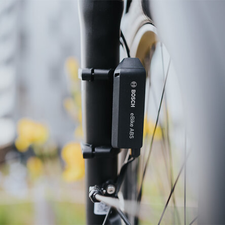 Nahaufnahme eines schwarzen Bosch eBike ABS-Sensors, der an der Gabel eines Fahrrads montiert ist.