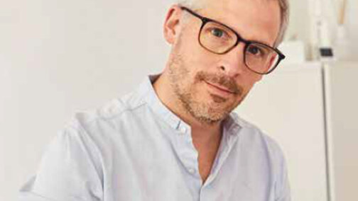 Philipp Hauser looks into the camera and writes on a clipboard.