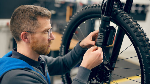 A bicycle technician is adjusting the brakes on an eBike.
