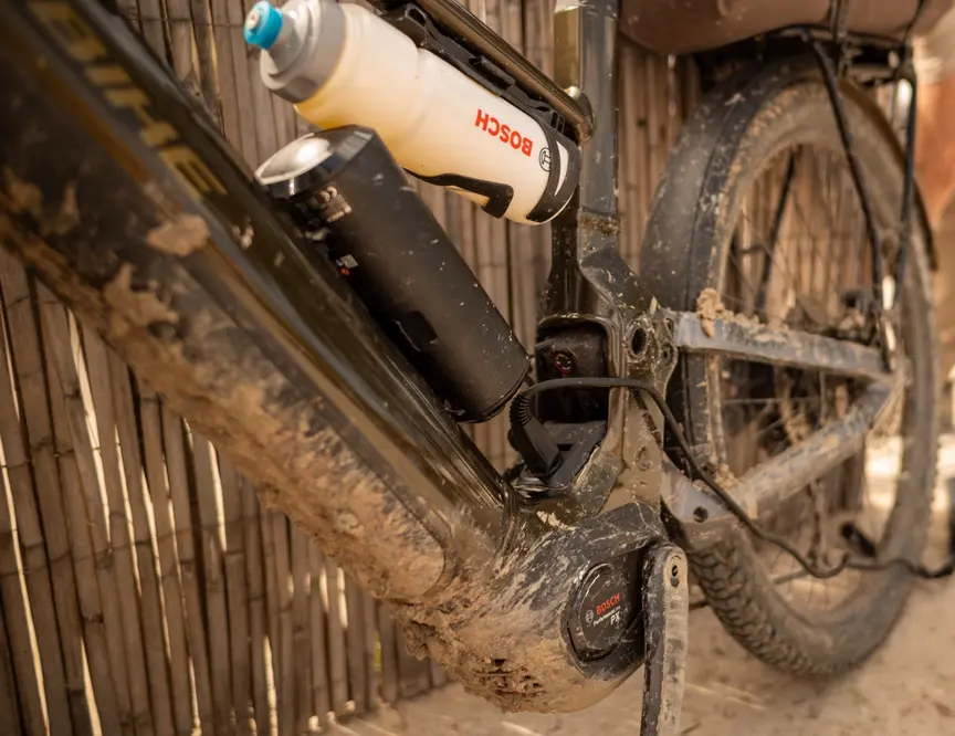 The mud-encrusted center of an e-bike reveals the powerful Bosch Performance Line CX drive unit and the battery after a demanding off-road tour.