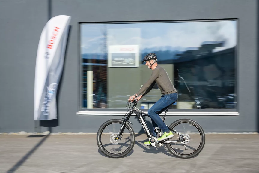 Ein eBike-Fahrer fährt an einem Bosch-Fahrradladen vorbei.
