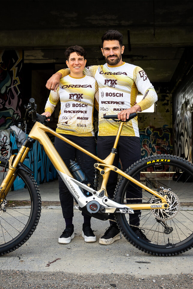 Florencia Espiñeira and Edgar Carballo from the Orbea Fox Enduro Racing Team stand arm in arm with their eBike.