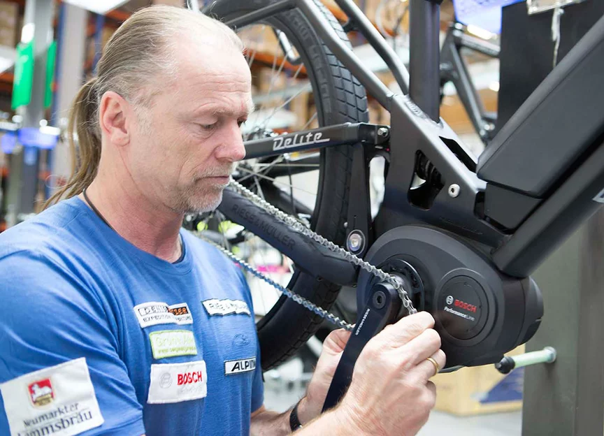 Zaměstnanec společnosti Bosch v dílně opravuje řetěz na eBike / elektrokolo.