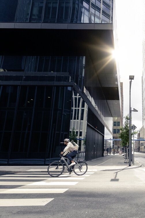 De man rijdt op zijn eBike door de straten van Frankfurt am Main, langs moderne gebouwen en stedelijke architectuur.