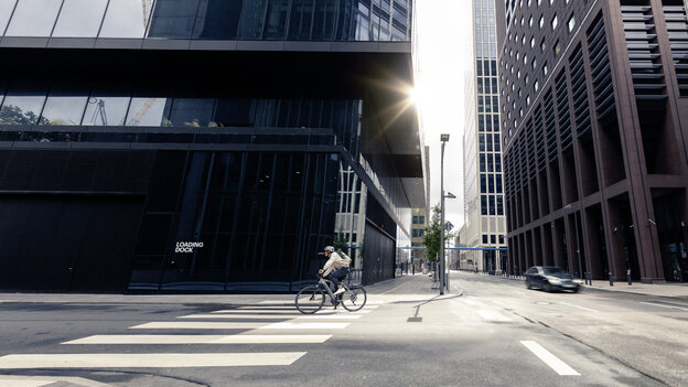 En man cyklar på sin eBike genom gatorna i Frankfurt am Main, förbi moderna byggnader och urban arkitektur.