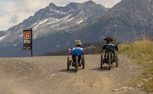 Tarek Rasouli rides his handbike alongside another mountain biker on a mountain trail. 