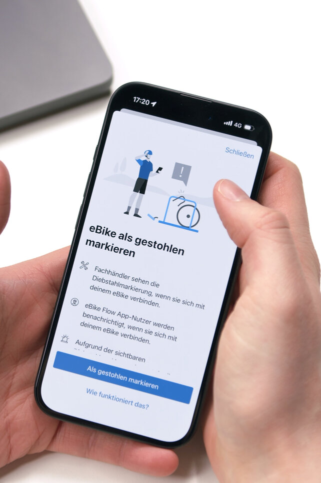Nahaufnahme eines Smartphones, das die Funktion 'eBike als gestohlen markieren' in der Bosch eBike Flow App anzeigt. Der Bildschirm erklärt, wie durch die Markierung Fachhändler und andere App-Nutzer bei einem Verbindungsversuch über den Diebstahl informiert werden.