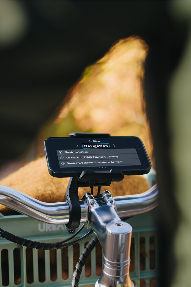 Blick auf den Lenker eines eBikes mit SmartphoneGrip und geöffneter Navigations-Einstellung auf dem Smartphone.