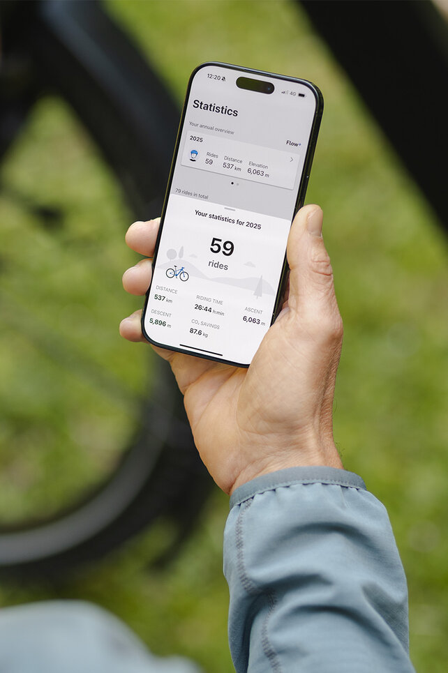 En person holder en smartphone i hånden og kigger på statistikkerne i eBike Flow-app.