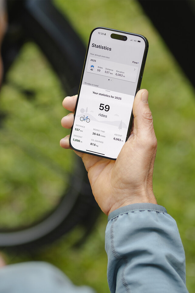 A person holds a smartphone and checks the statistics in the eBike Flow app.