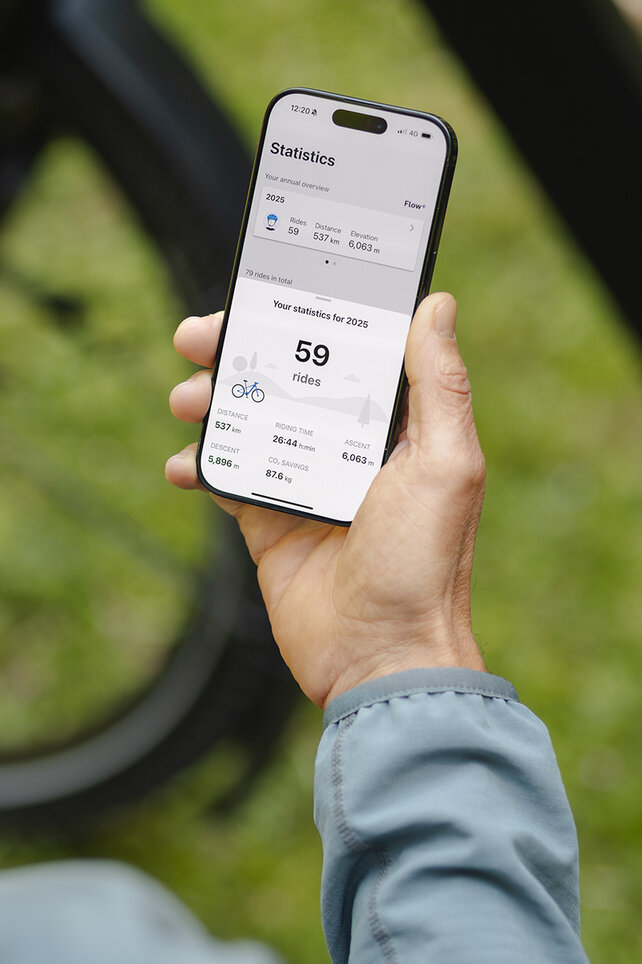 En person holder en smarttelefon i hånden og ser på statistikken i eBike Flow-app.