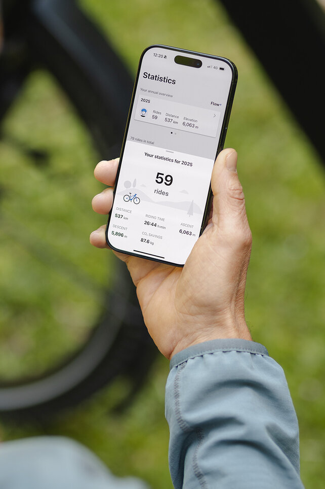 En person håller en smartphone i handen och tittar på statistiken i eBike Flow-app.